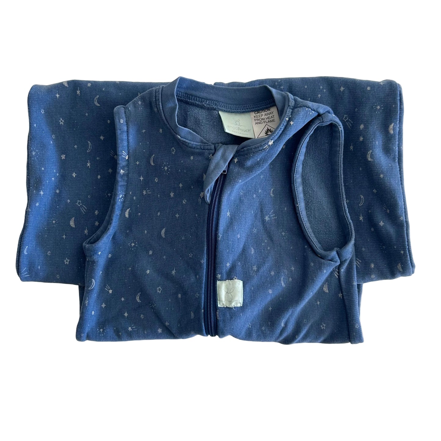 A folded baby sleep sack in dark blue with a white moon and star pattern, featuring a front zipper and a small white brand tag near the hem.
