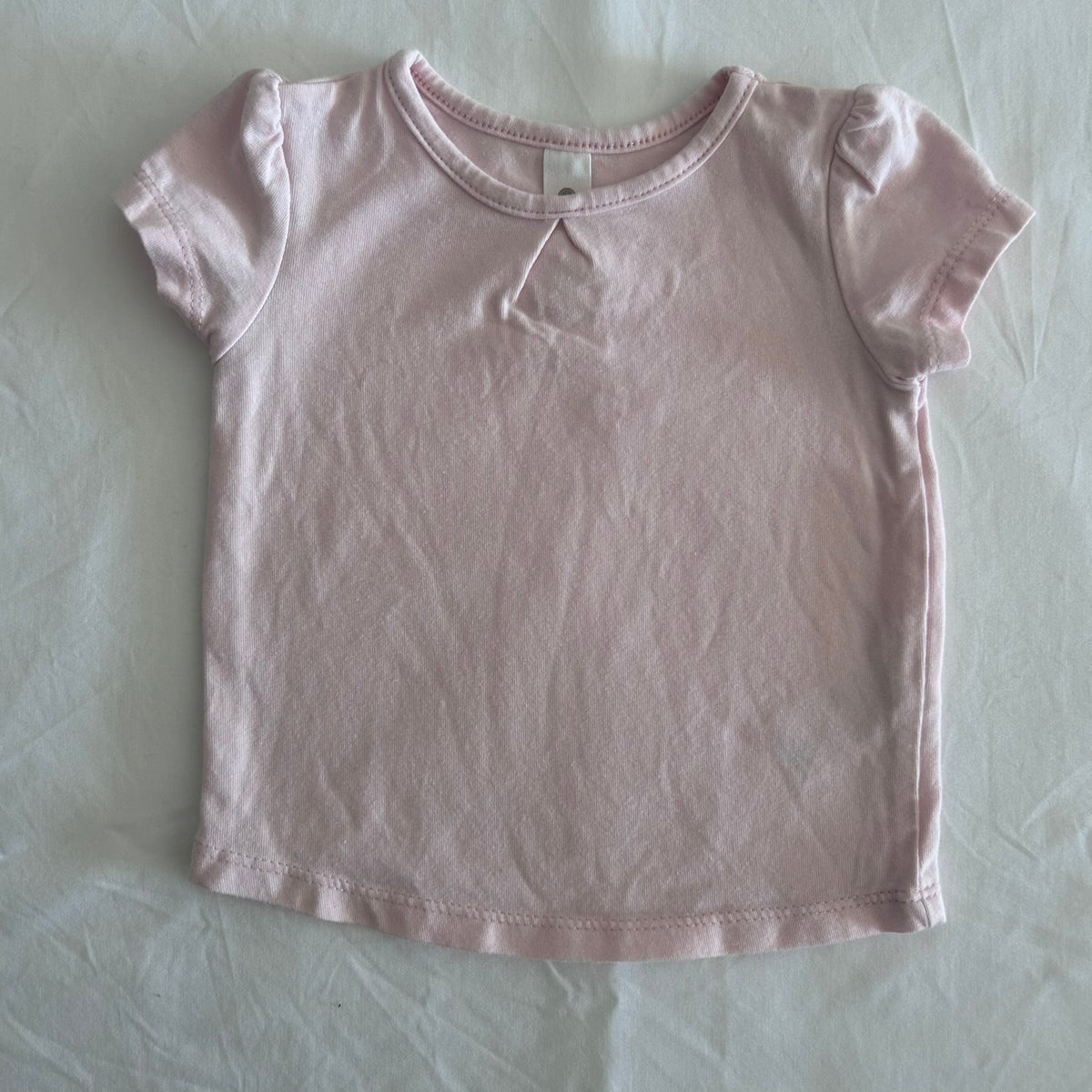 Dymples Age 000 short sleeve t-shirt in light pink with ruffle sleeve trim, small pleat detail at neckline — gently loved condition.
