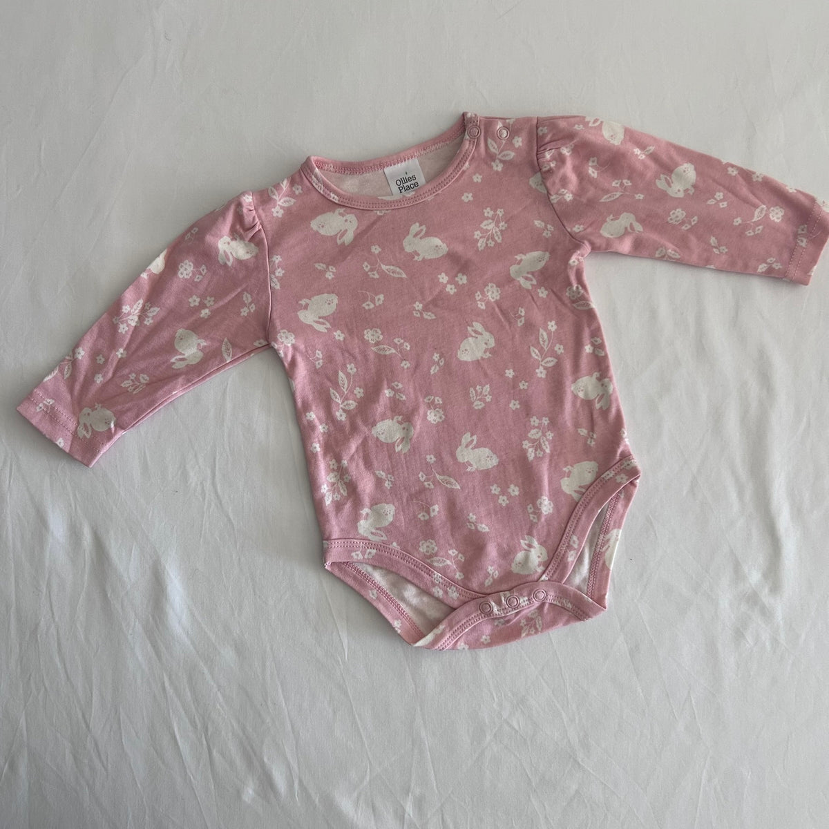 Ollie's Place Age 00 long sleeved bodysuit in pink with allover white bunny and floral print, gently loved condition.
