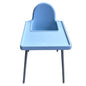 A light blue plastic baby high chair with a tray and silver metal legs, photographed outdoors on a tiled patio against a white wall.