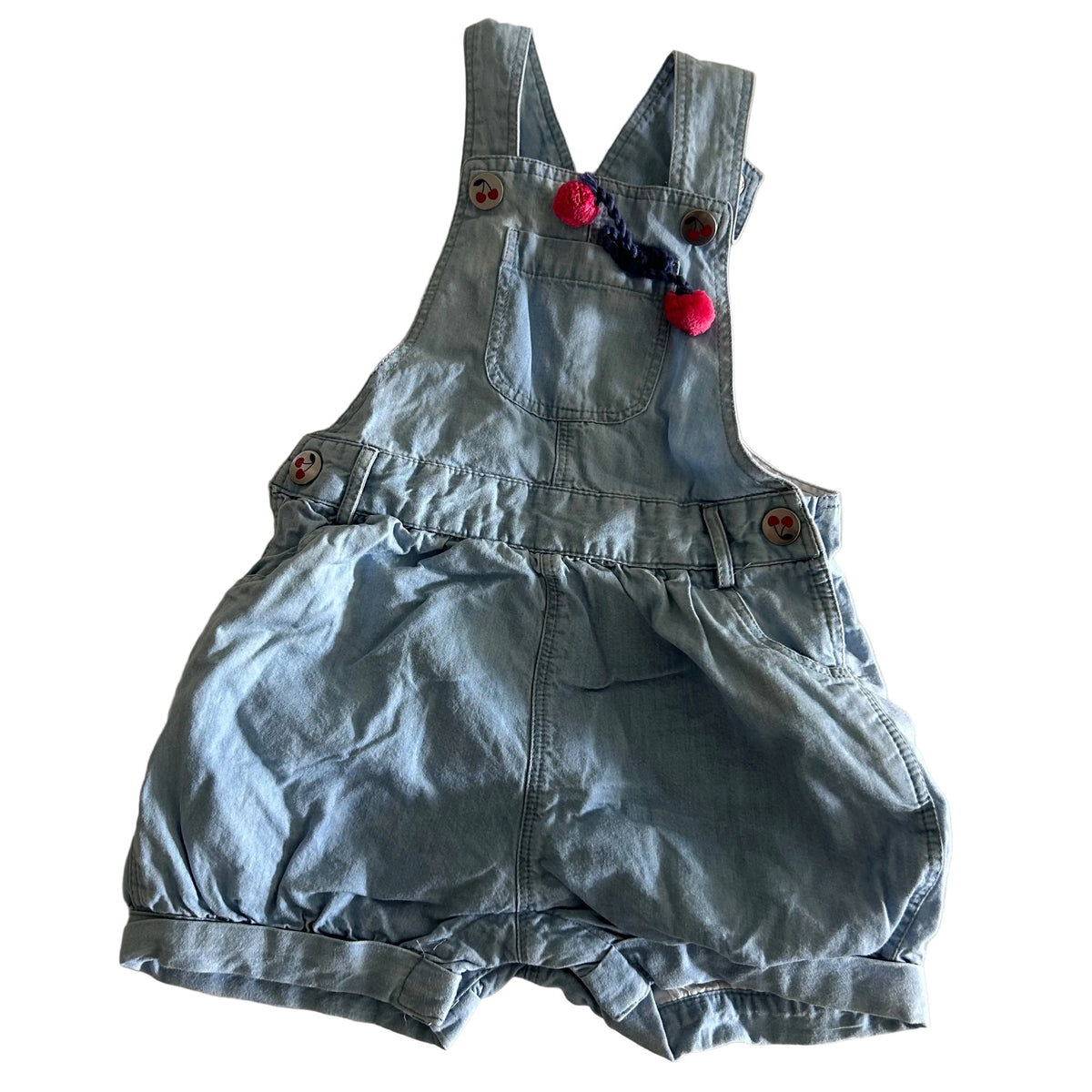 Jack & Milly Age 00 sleeveless denim dungaree shortalls in light blue with cherry print buttons, pink pom pom and navy braided trim detail — gently loved condition.