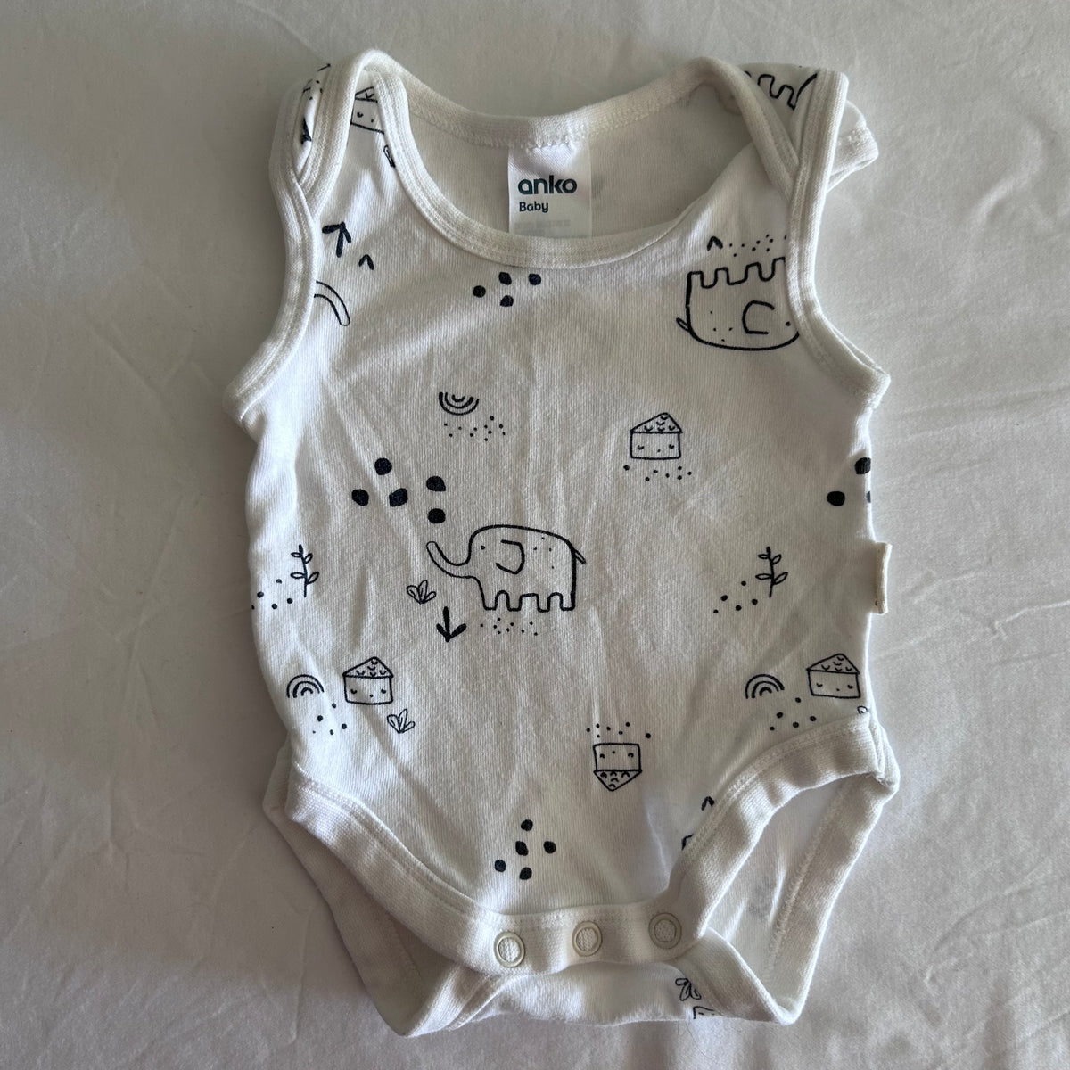 Anko Baby Age 00000 sleeveless bodysuit in white with black print with allover illustrated print featuring elephants, castles, houses, rainbows, arrows, dots and small plants — gently loved condition.