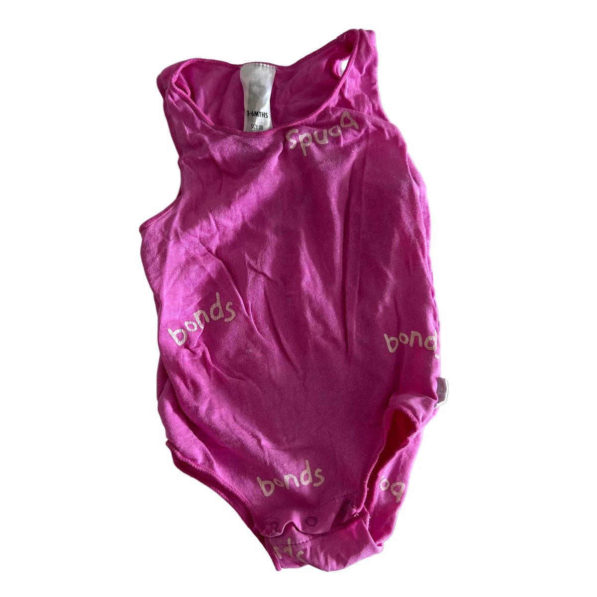 Bonds Age 00 sleeveless bodysuit / onesie in hot pink with all-over 'bonds' logo print in gold/cream text — gently loved condition.