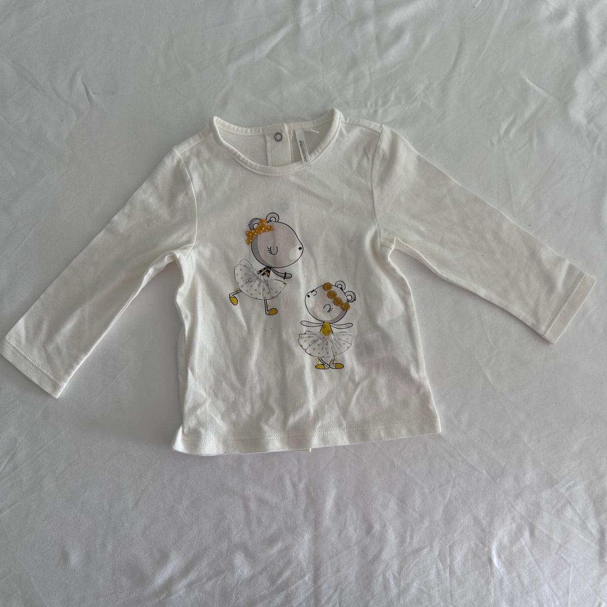 Orchestra Age 1 long sleeved top in white with two illustrated bear ballerina characters with yellow/gold bows and tulle skirt details — like new condition.