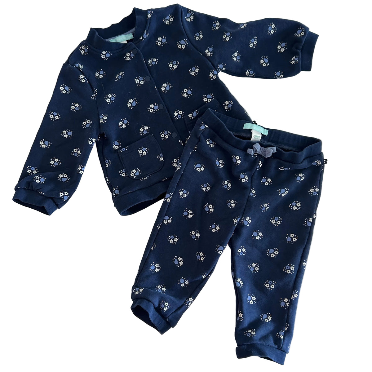 Obaïbi Age 2 two-piece tracksuit set (button-up jacket and jogger pants) in navy blue with allover small floral clusters (white, light blue, and orange flowers with blue dot centres) — like new condition.