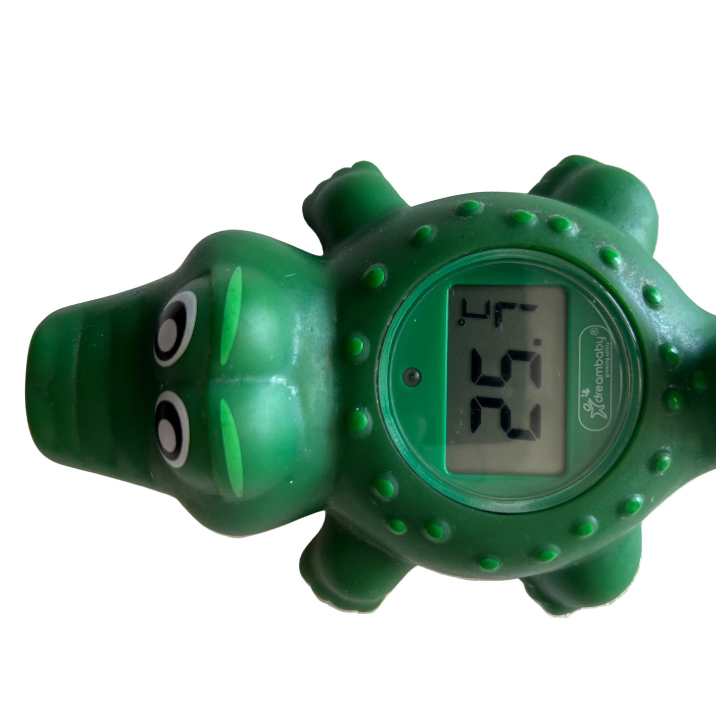 A green alligator-shaped bath thermometer with a screen showing a temperature, mounted on a white textured wall.