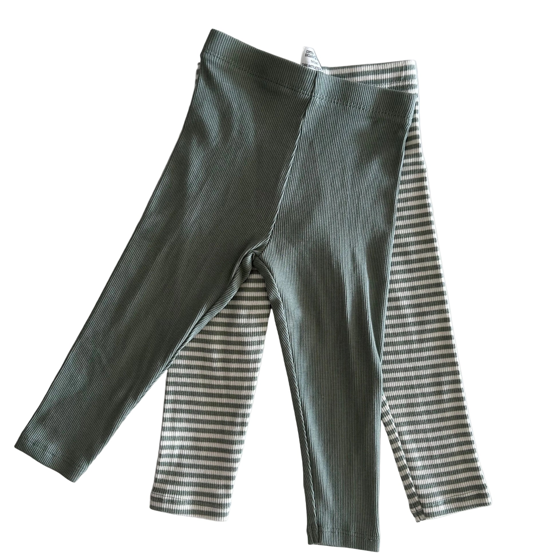 Green ribbed leggings on top of striped leggings on a light background