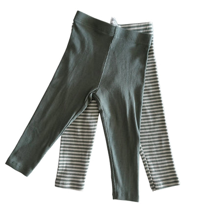 Green ribbed leggings on top of striped leggings on a light background