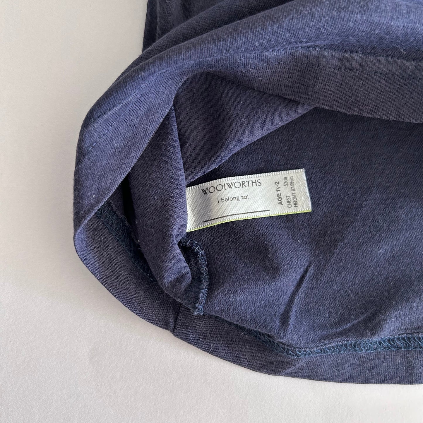 Close-up of inside of blue t-shirt with a label on a pale background