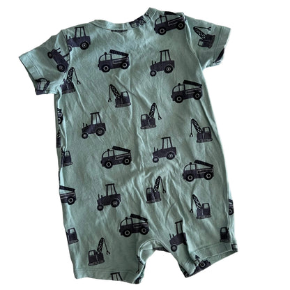 Green baby romper with black construction vehicle pattern on a white background