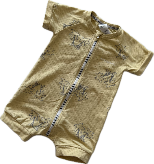 Mustard yellow baby romper with short sleeves and palm tree pattern on pale background