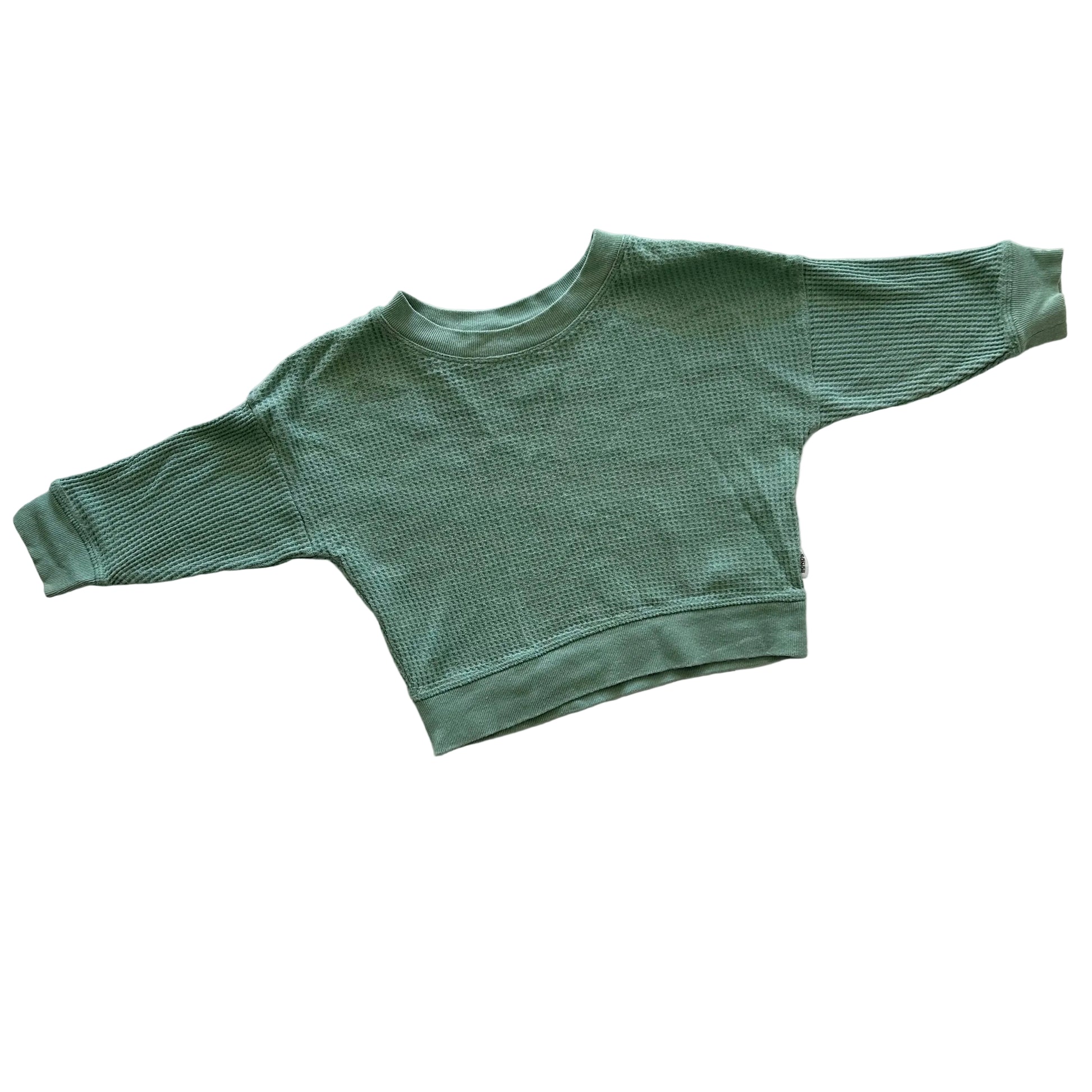 A green waffle knit style long-sleeve jumper laid flat on a white background.