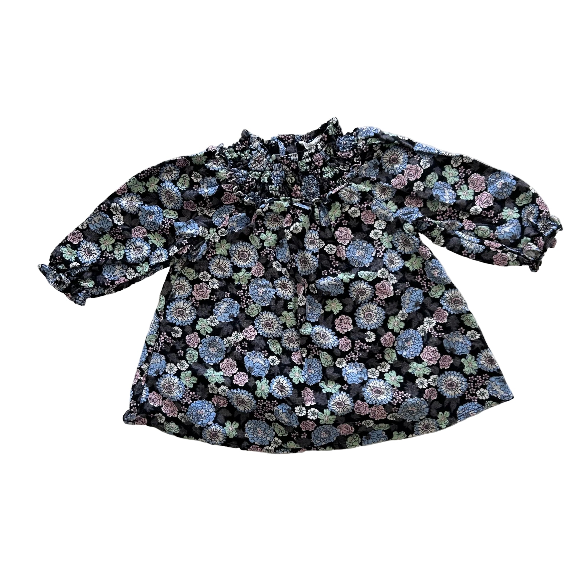 A long-sleeve blouse with a dense floral pattern in shades of blue, pink, and green on a black background, laid flat on a white background.