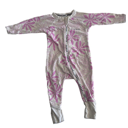 The front of a light pink baby onesie with long sleeves and legs, featuring a darker pink floral pattern, laid flat on a white surface.