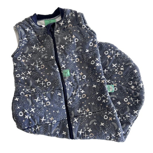 A sleeveless quilted sleeping bag laid flat on a white background, featuring a dark gray and navy blue space-themed print with stars, moons, and a white-and-black tic-tac-toe pattern. 