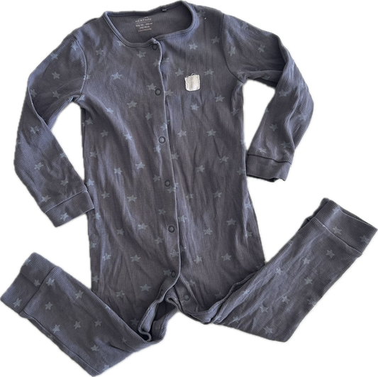A button up onesie laid flat on a white background, featuring long sleeves, legs folder upwards, purple grey colour and stars and crescent moon pattern.