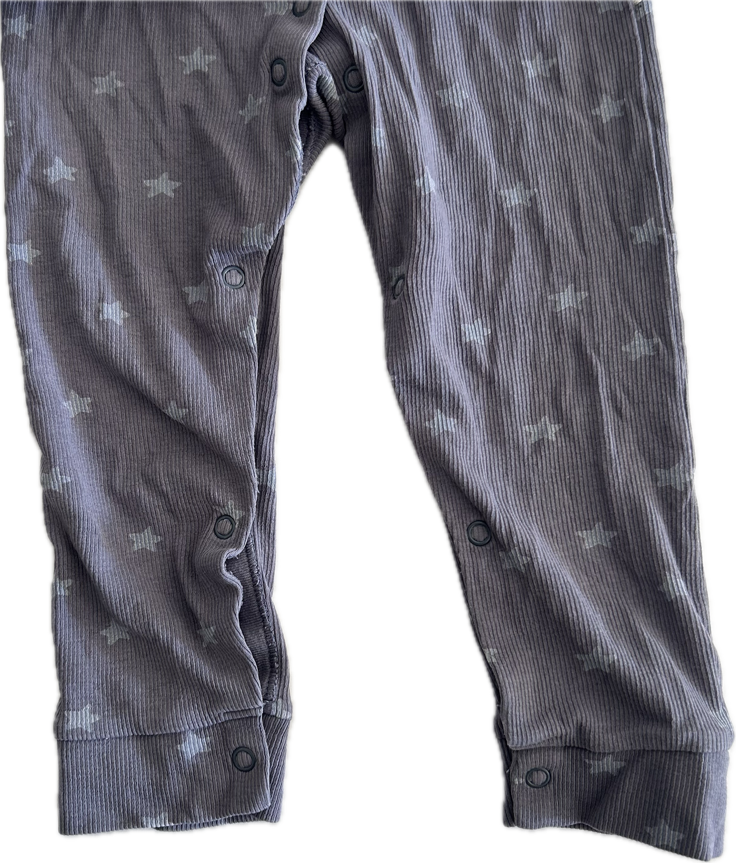 Close up photo of the legs of a purple-grey baby onesie with button up legs. 
