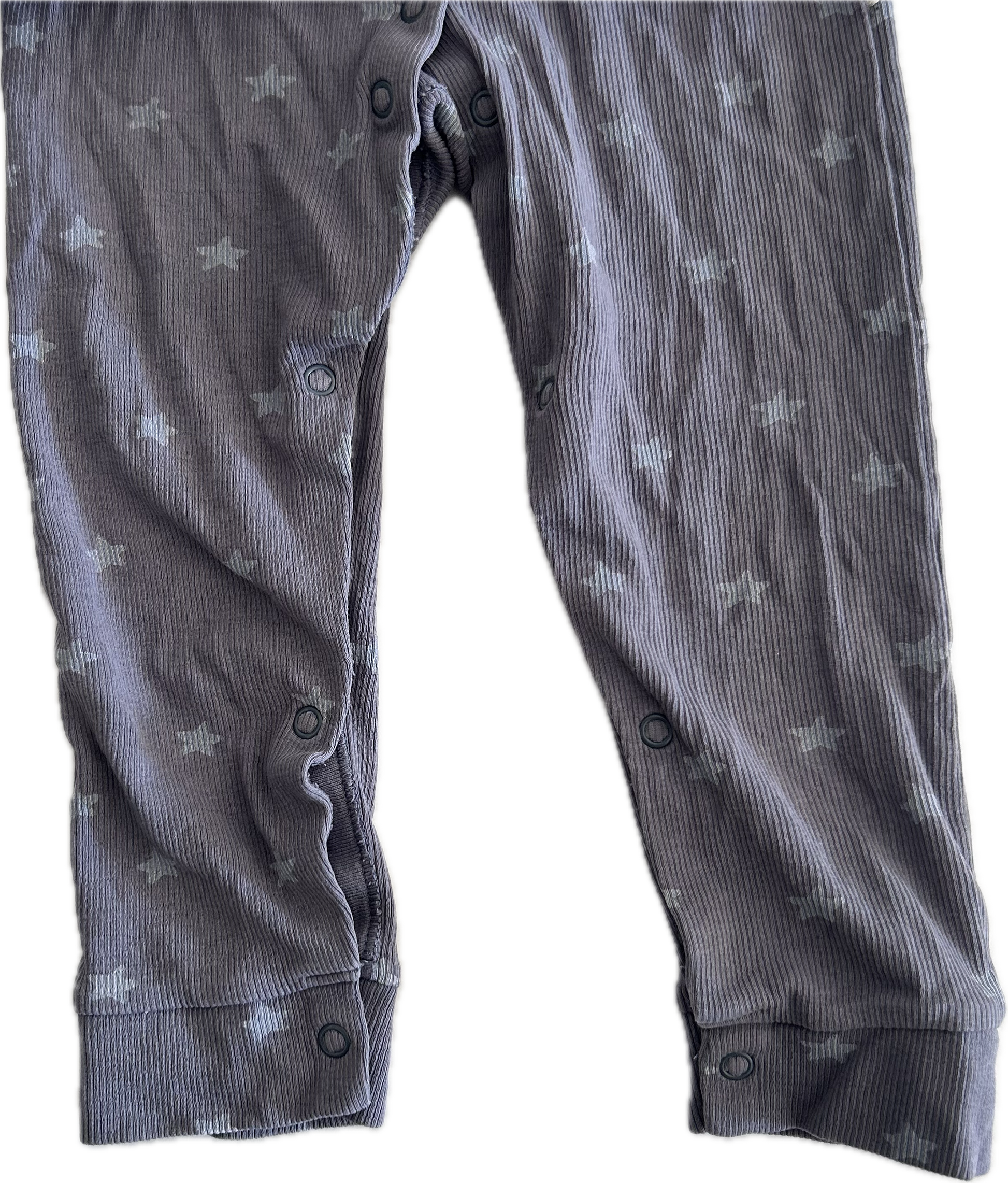 Close up photo of the legs of a purple-grey baby onesie with button up legs. 