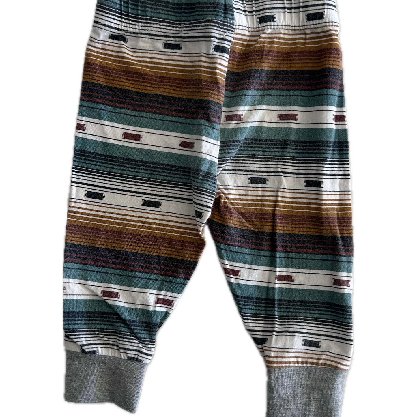The back of pair of children's striped trousers with horizontal bands of brown, green, grey, black, and white, featuring ribbed ankle cuffs.