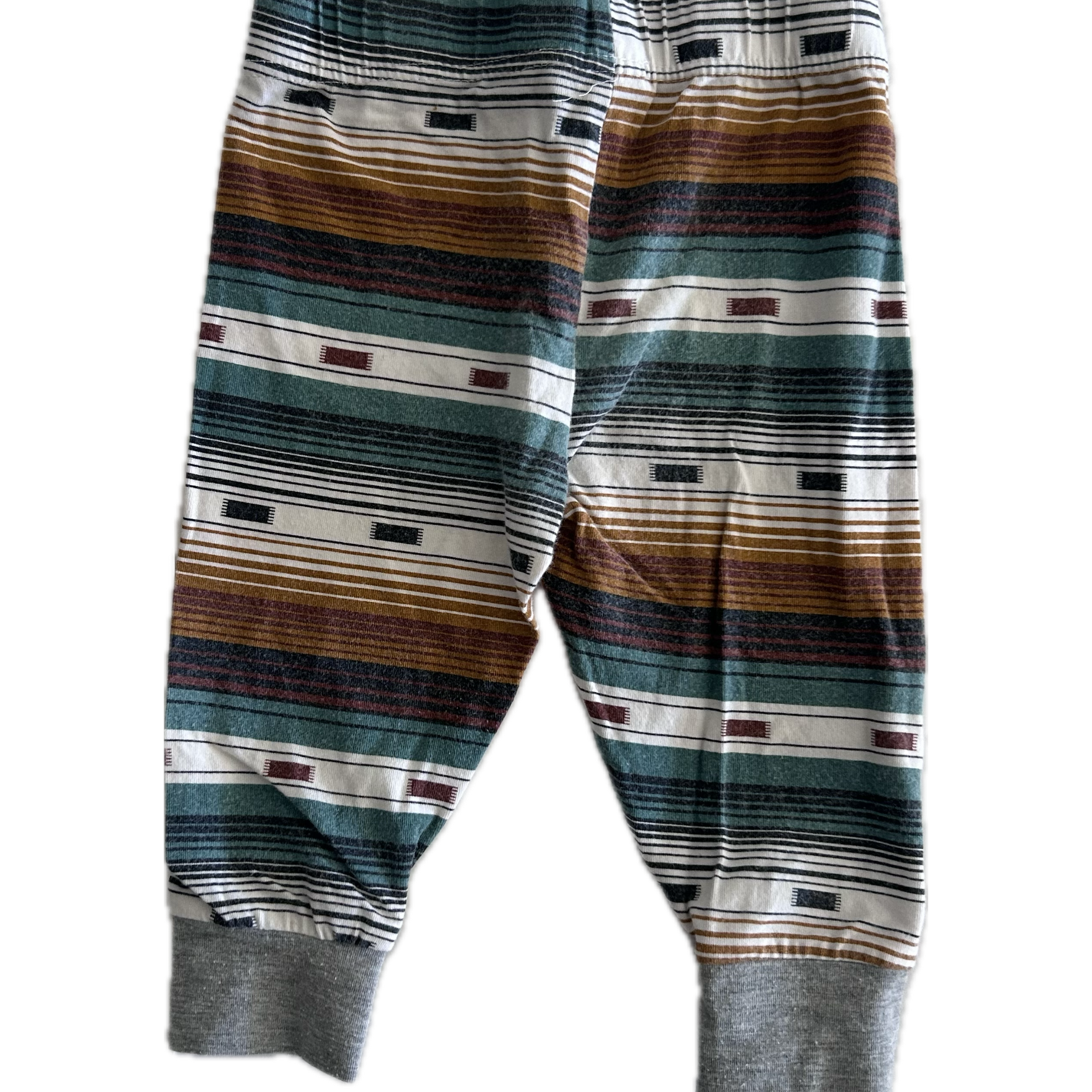 The back of pair of children's striped trousers with horizontal bands of brown, green, grey, black, and white, featuring ribbed ankle cuffs.