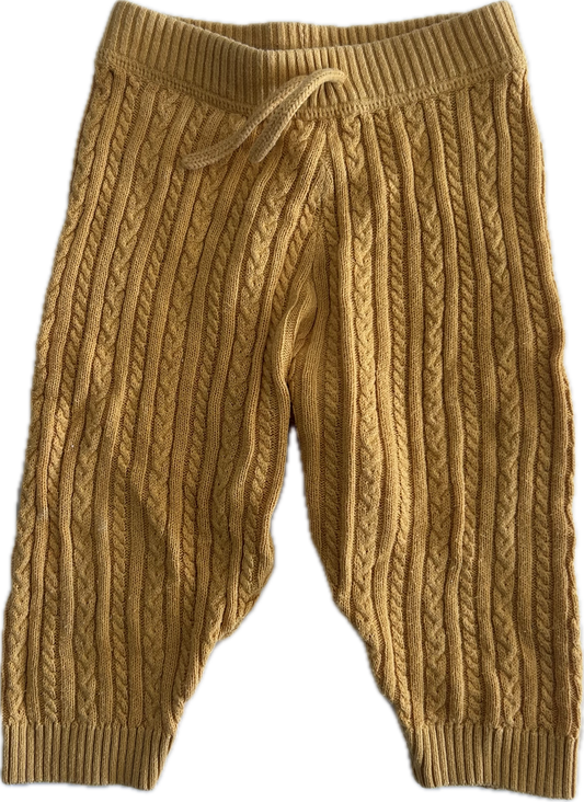 A pair of mustard yellow cable-knit baby pants with an elastic waistband and drawstring, shown against a plain white background.