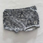 A pair of shorts with a navy blue and white wave and sailboat pattern, laid flat on a white fabric background.