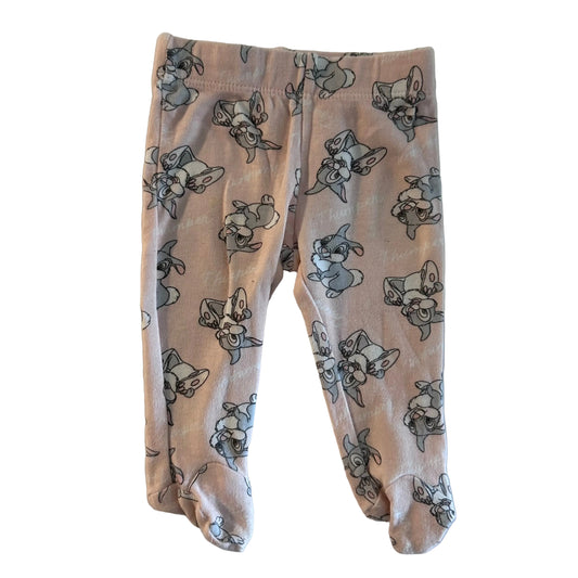 Baby footed leggings in a light pink fabric with an all-over print of cartoon rabbits in grey and black outlines, laid flat on a light surface.