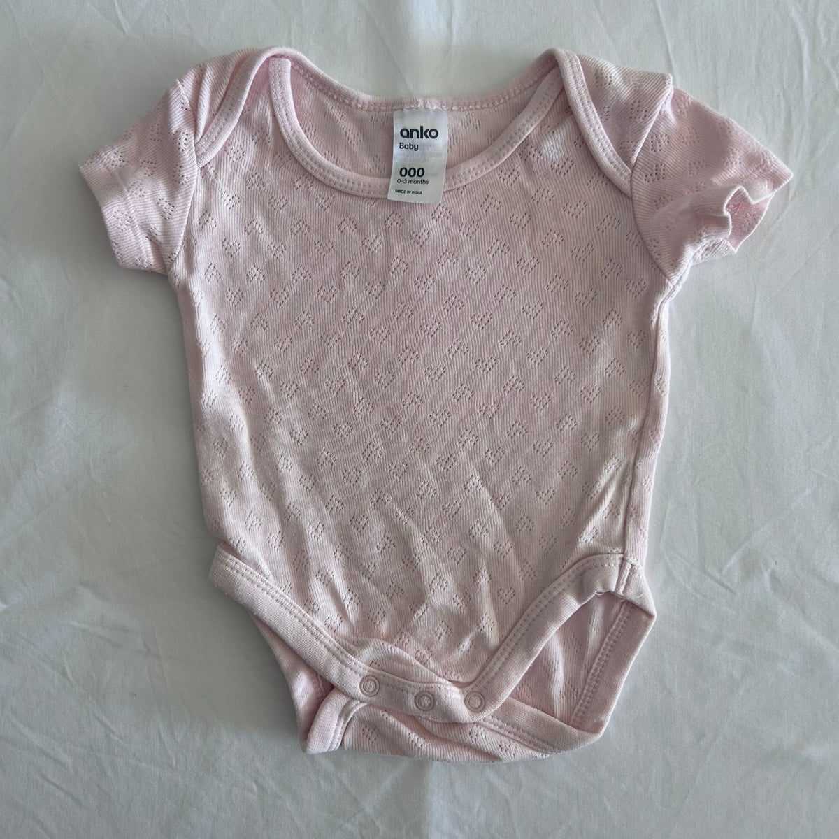 Anko Age 000 short sleeve bodysuit in pink with pointelle knit diamond texture â€” gently loved condition.