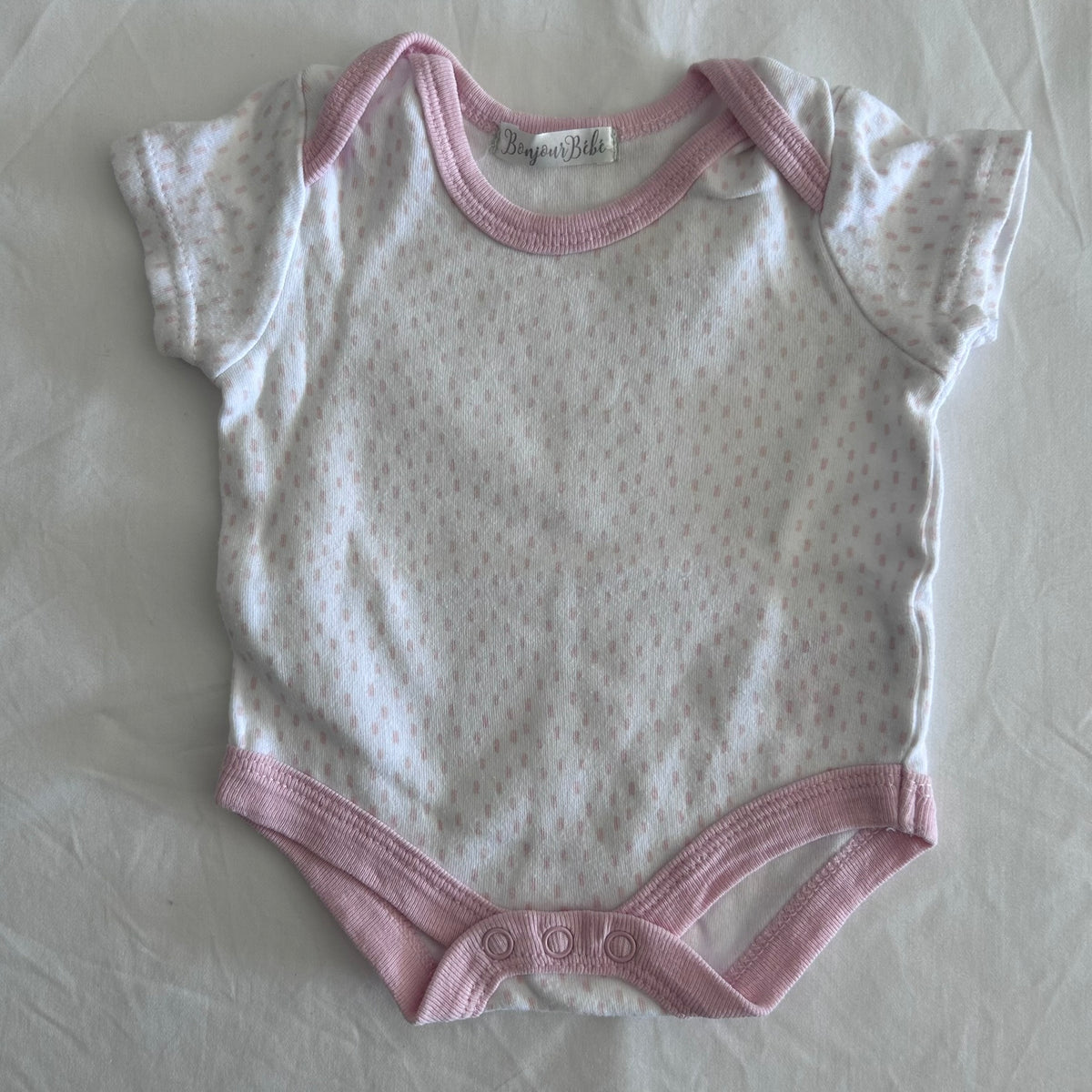 Bonjour BÃ©bÃ© Age 000 short sleeve snap-crotch bodysuit in white and pink with pink polka dots with pink trim â€” gently loved condition.