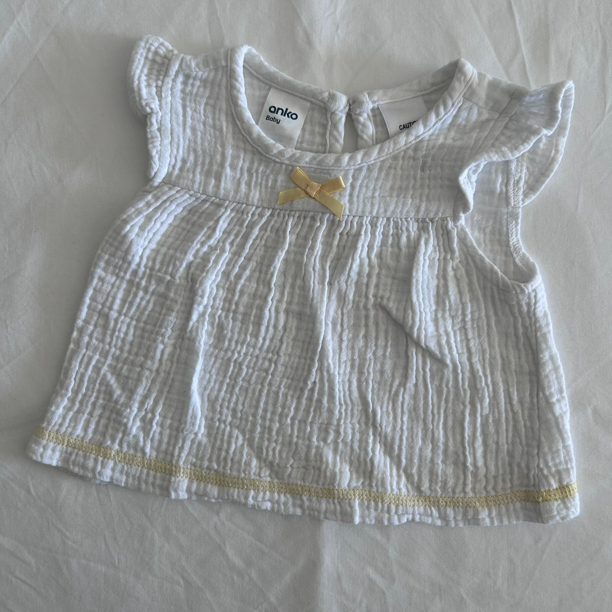 Anko Age 000 flutter sleeve dress in white with yellow trim with crinkle/muslin texture, yellow satin bow at neckline, yellow ribbon trim at hem â€” gently loved condition.
