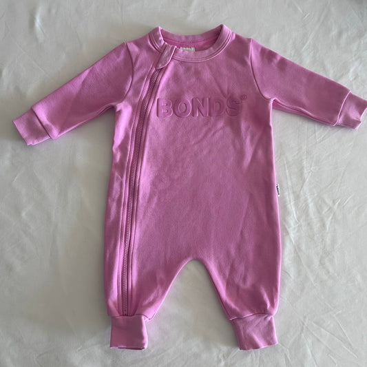 Bonds Age 000 long sleeved zip-up onesie in pink with embossed bonds logo on chest â€” gently loved condition.
