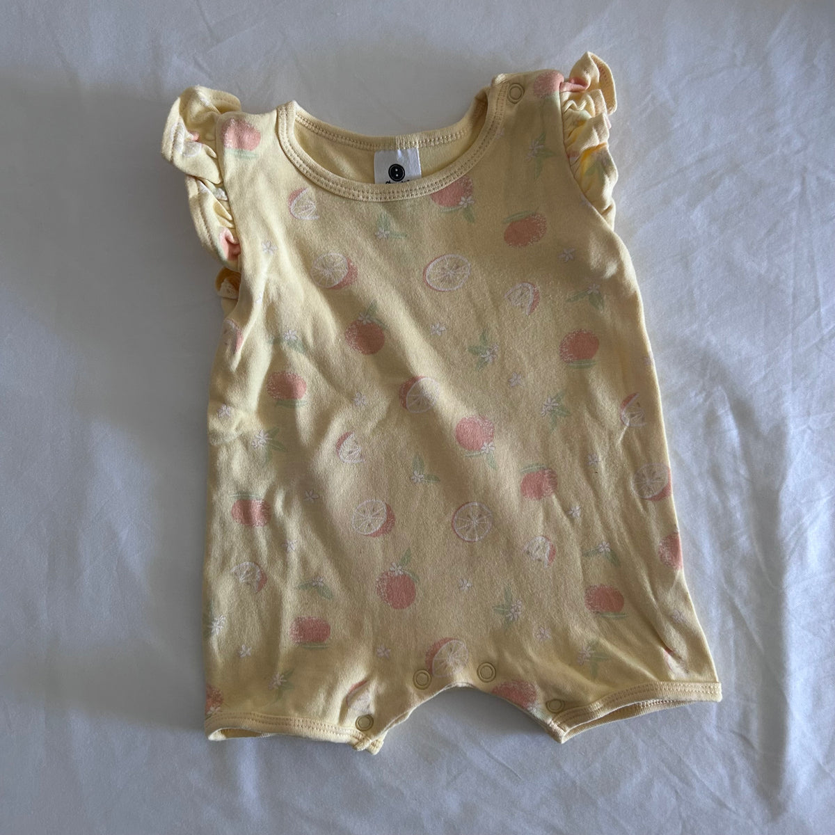 Dymples Age 000 romper in yellow, pink, green, white with citrus fruit print (oranges, lemons, sliced citrus), short sleeved â€” gently loved condition.