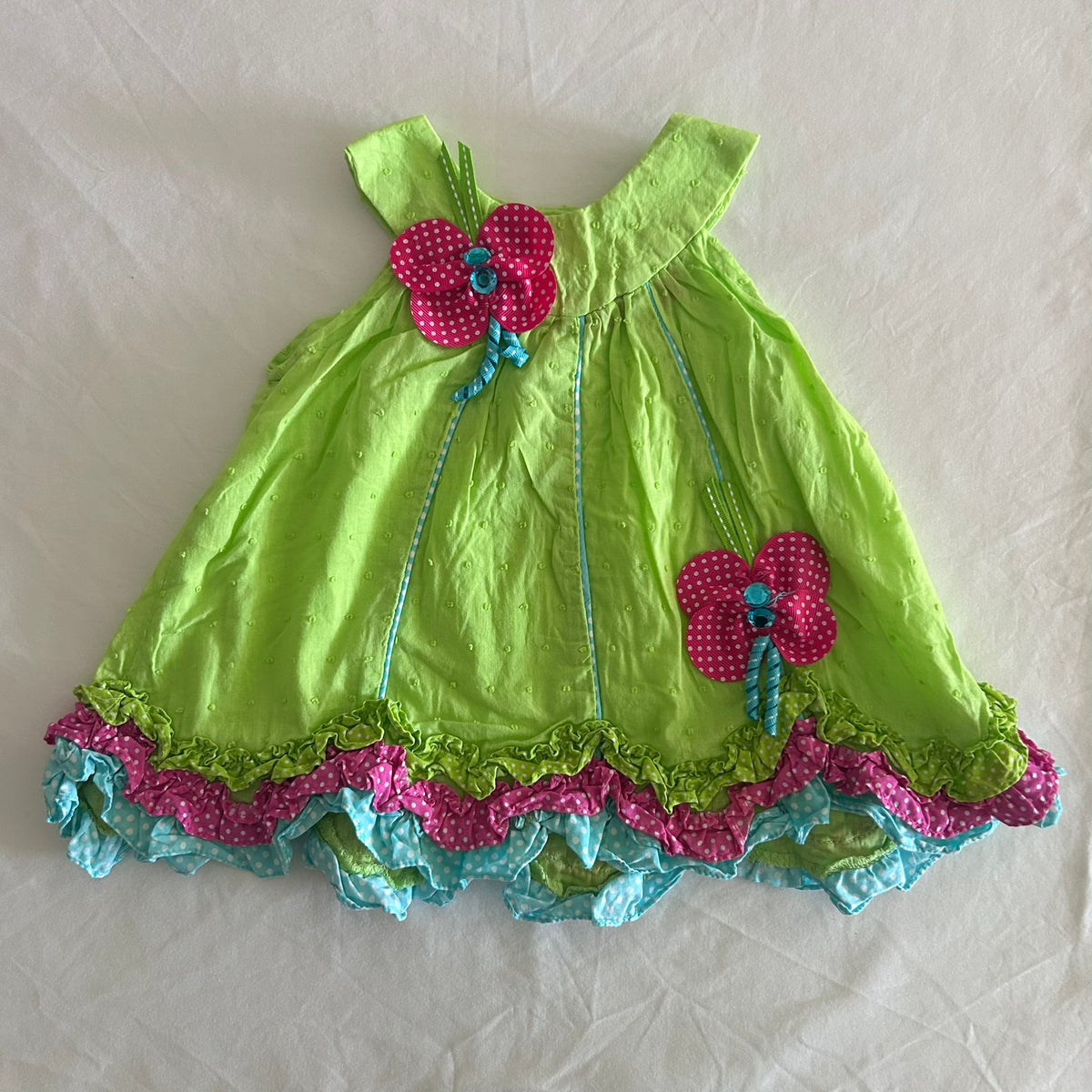 Dolish Age 000 dress in lime green, hot pink, turquoise with swiss dot fabric, polka dot ribbon flower appliquÃ©s, tiered ruffle hem, ribbon trim â€” gently loved condition.