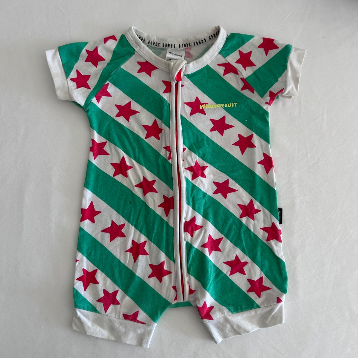 Bonds Age 00 short sleeve zip romper in white, green, pink with diagonal stripes with stars â€” gently loved condition.