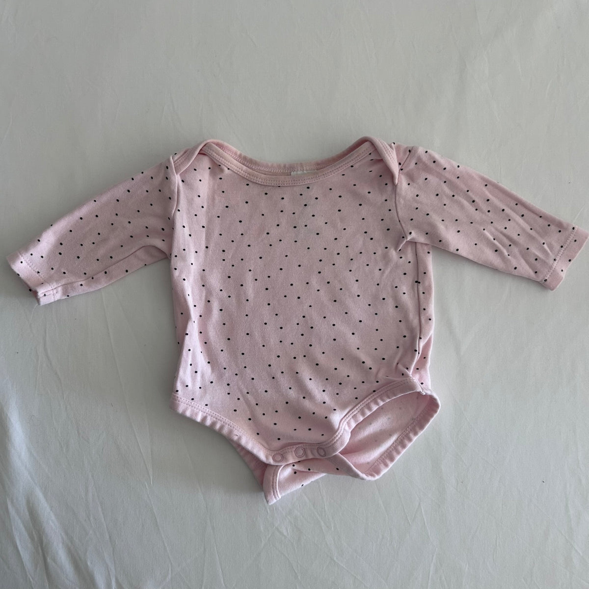 Dymples Age 00 long sleeved snap-crotch bodysuit in pink with small black polka dots, well loved condition.