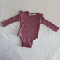La Sienna Couture Age 00 long sleeve ribbed bodysuit in dusty pink with ribbed texture, frill/ruffle shoulder detail, gently loved condition.