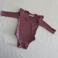 La Sienna Couture Age 00 long sleeve ribbed bodysuit with frill shoulder detail in dusty rose pink with ribbed texture with decorative frill at shoulders, gently loved condition.
