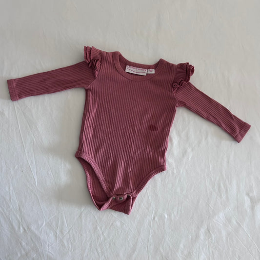 La Sienna Couture Age 00 long sleeve ribbed bodysuit in dusty pink with ribbed texture with frill shoulder detail, gently loved condition.