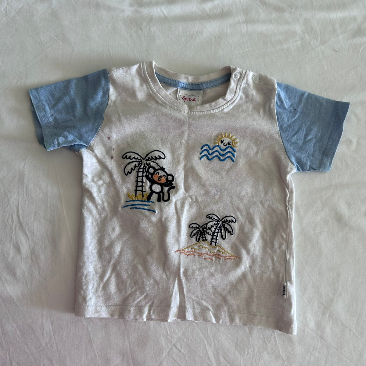 Sprout Age 1 short sleeve t-shirt in white and light blue with embroidered beach scene — monkey climbing palm tree, palm trees, waves, and sun motifs — well loved condition.