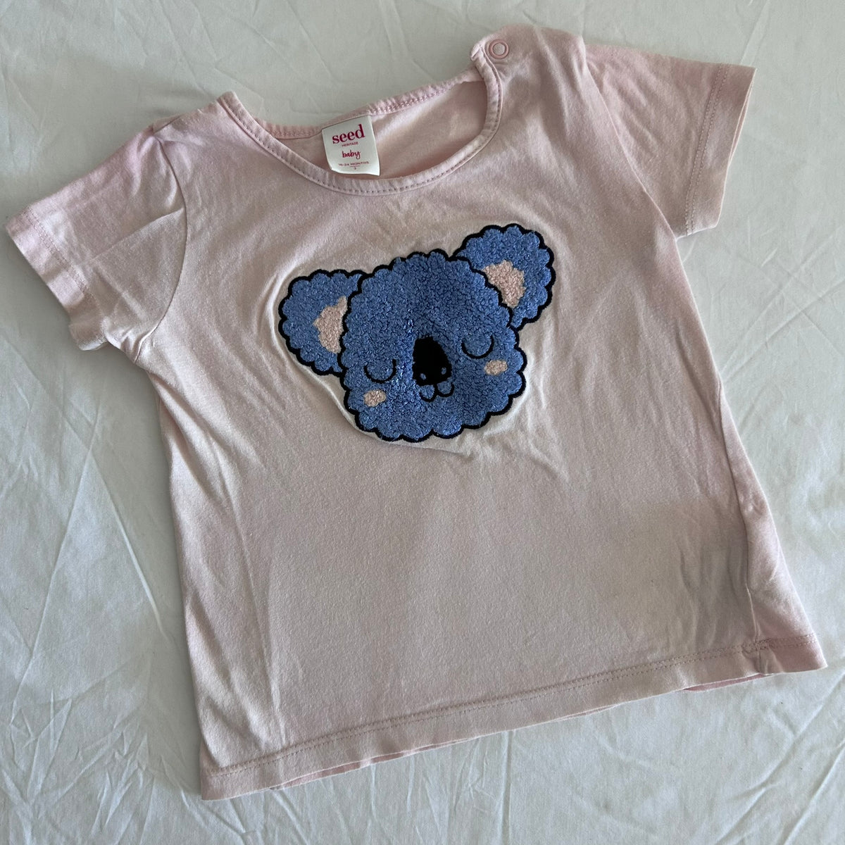 Seed Heritage Age 1 short sleeve t-shirt in light pink, blue, beige with textured chenille koala face appliqué on front — gently loved condition.