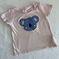 Seed Heritage Age 1 short sleeve t-shirt in light pink, blue, beige with textured chenille koala face appliqué on front — gently loved condition.