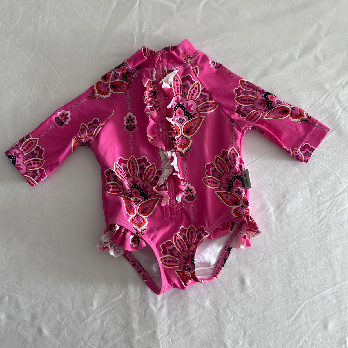 Country Road Age 000 long sleeve one-piece swimsuit in hot pink, red, purple, white, black with paisley/mandala floral print with front zip and ruffle trim — gently loved condition.