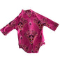 A pink long-sleeve baby bodysuit with a colorful mandala pattern, laid flat on a white fabric background.