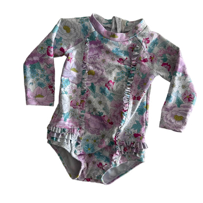 Bebe by Minihaha Age 00 long sleeve zip-up swimsuit / rashie one-piece in white, pink, lilac, teal with floral print with ruffle trim on front, hem and leg openings — gently loved condition.