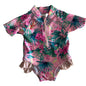 Baby Berry Age 00 short sleeve zip-up one-piece swimsuit with frill trim in pink, green, teal, magenta, yellow with tropical floral and palm leaf print, ruffle/frill detail at bottom hem — gently loved condition.