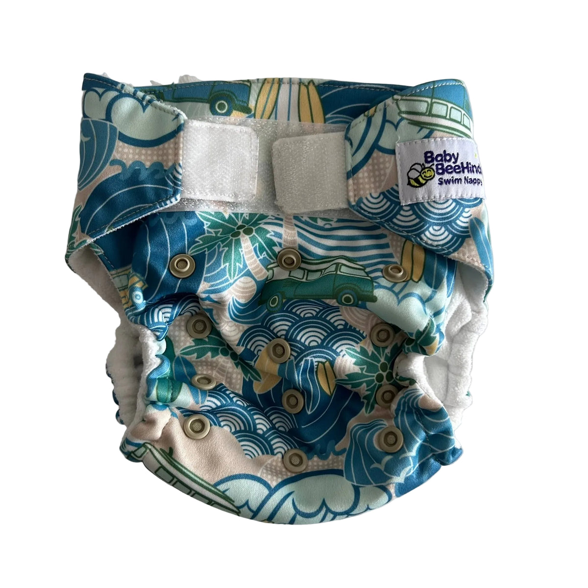 A reusable cloth swim diaper with a blue, green, and beige wave pattern, featuring two white hook-and-loop fastening closures and a white brand label that reads 'Baby Beating Swim Diaper'.
