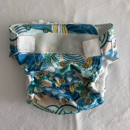 Baby BeeHinds Age 00 swim nappy in blue, teal, white, beige, yellow, green with surf/beach print with waves, palm trees, surfboards and vintage cars — gently loved condition.