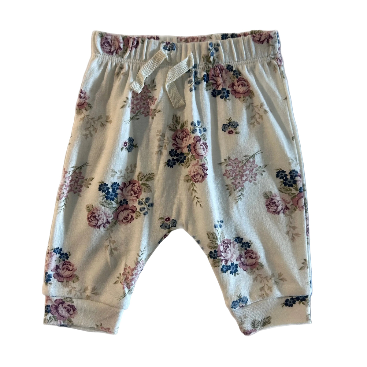 A pair of baby bloomers with an elastic waistband and drawstring, featuring a pink, blue, and green floral pattern on a cream-colored fabric, laid flat on a white background.